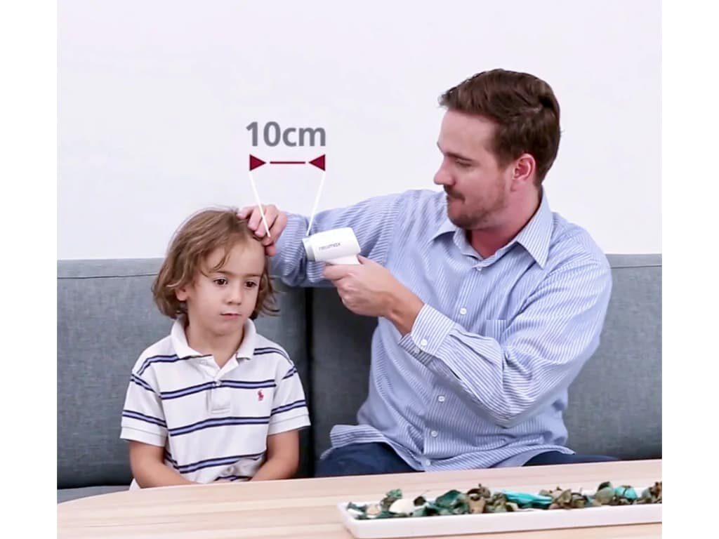 Man meet de voorhoofdtemperatuur van een kind met de Rossmax HC700 BT contactloze thermometer met een afstandslijn en de tekst “10cm” in beeld