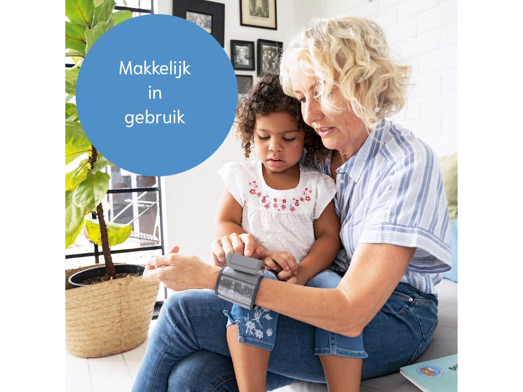 Vrouw zit met kind op schoot met de Beurer BC 27 polsbloeddrukmeter om haar pols, met een cirkel met de tekst “Makkelijk in gebruik” in beeld