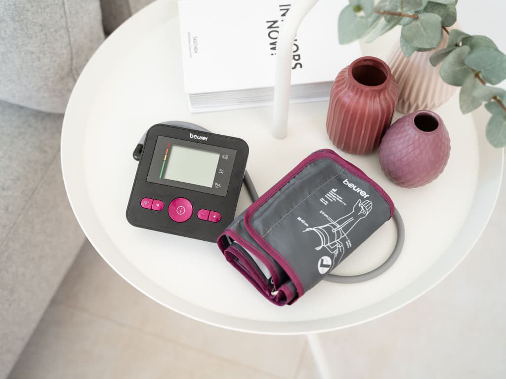 Beurer BM 27 Limited Edition zwart/roze bovenarm bloeddrukmeter met manchet op een tafeltje