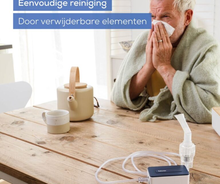 Man zit aan tafel met een zakdoek voor zijn neus en een handdoek om, Beurer IH 15 vernevelaar op tafel