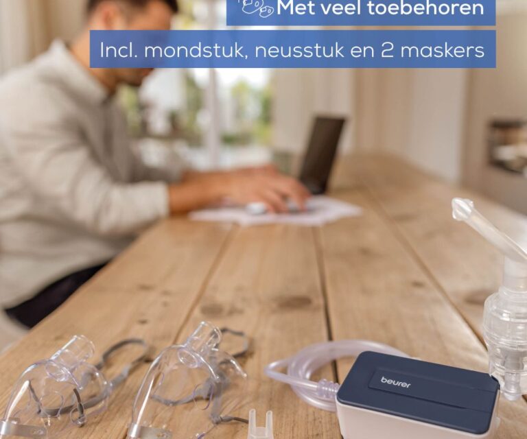 Beurer IH 15 vernevelaar met accessoires op tafel, man werkt op laptop op de achtergrond