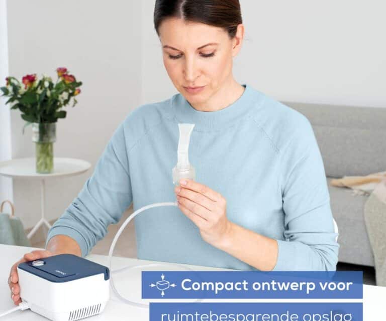 Vrouw zit aan tafel met de Beurer IH 16, houdt het mondstuk vast dat via een slang is verbonden