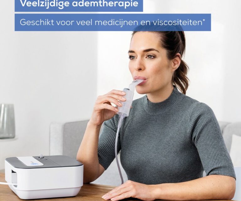 Vrouw zit aan tafel en gebruikt de Beurer IH 28 Pro vernevelaar met het mondstuk in de mond