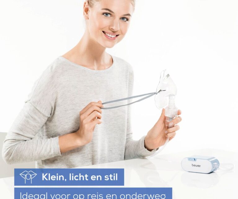 Vrouw zit aan tafel met de Beurer IH 60 en houdt een volwassenmasker vast